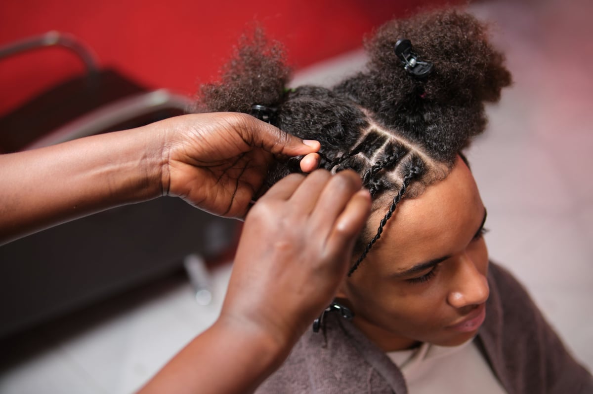 Hairstylist braiding cornrows in a salon setting