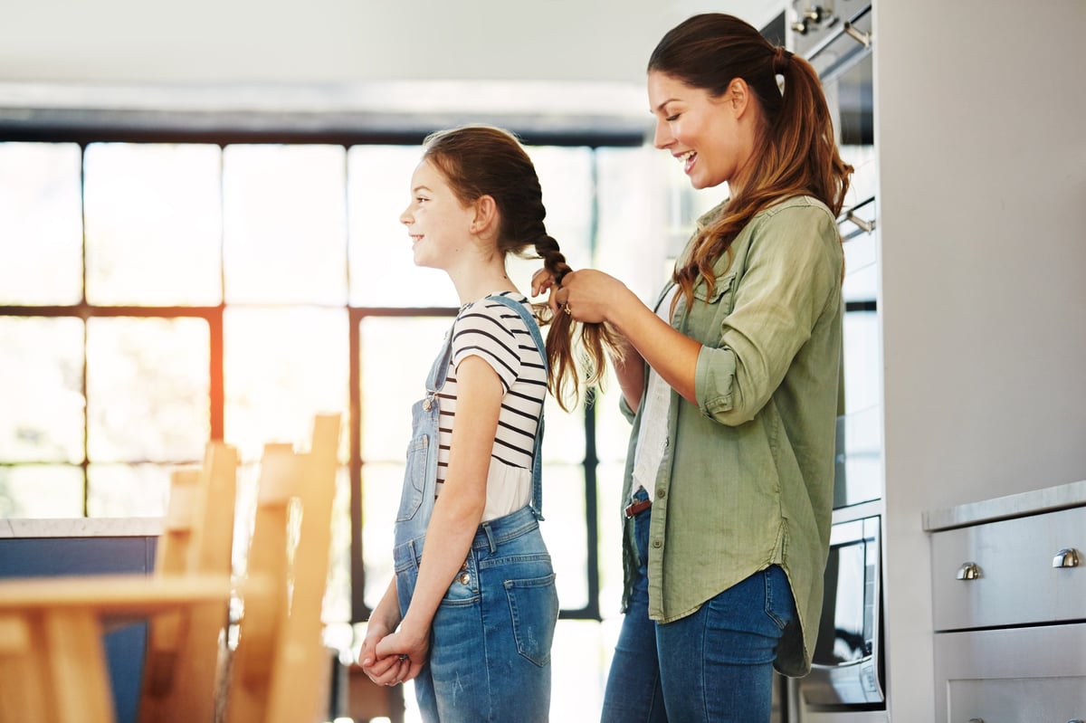 Mother styling a child's braided hair at home